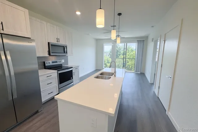 a kitchen with stainless steel appliances a refrigerator a stove a sink dishwasher a oven with a dining table and chairs with wooden floor