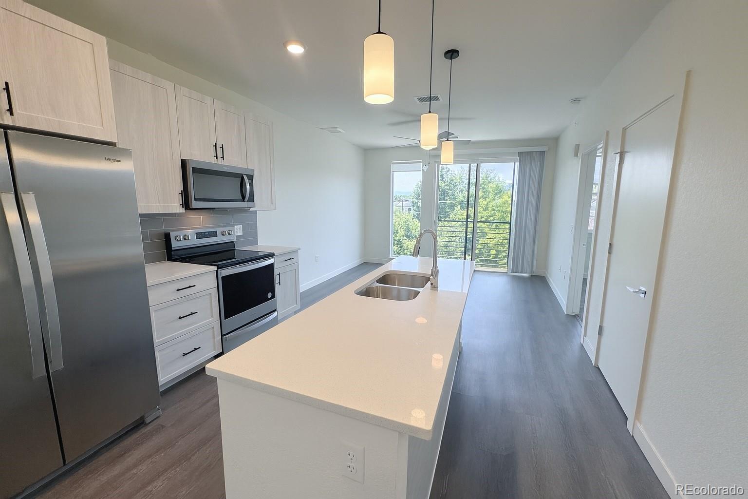 4900 West 29th Avenue, Unit 310 Denver, CO 80212 - Photo 2 of 13 a kitchen with stainless steel appliances a refrigerator a stove a sink dishwasher a oven with a dining table and chairs with wooden floor