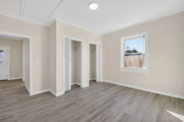 an empty room with wooden floor and windows