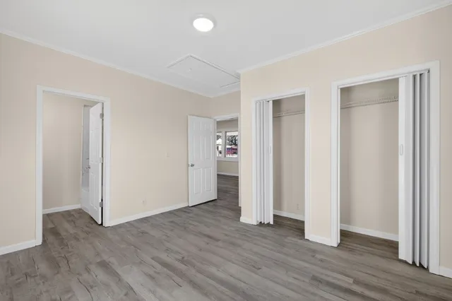 an empty room with wooden floor & closet and windows