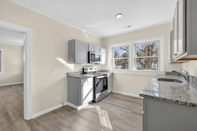 a kitchen with granite countertop a stove a sink and a refrigerator