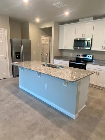 a kitchen with stainless steel appliances granite countertop a sink a stove top oven a refrigerator and a granite counter tops