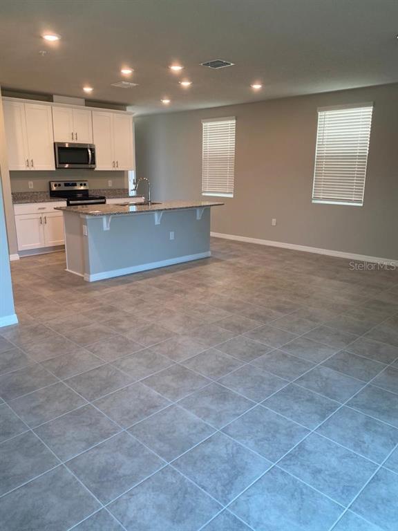 2053 Milkweed Street Ocoee, FL 34761 - Photo 6 of 17 a kitchen with kitchen island granite countertop a stove a sink and a microwave