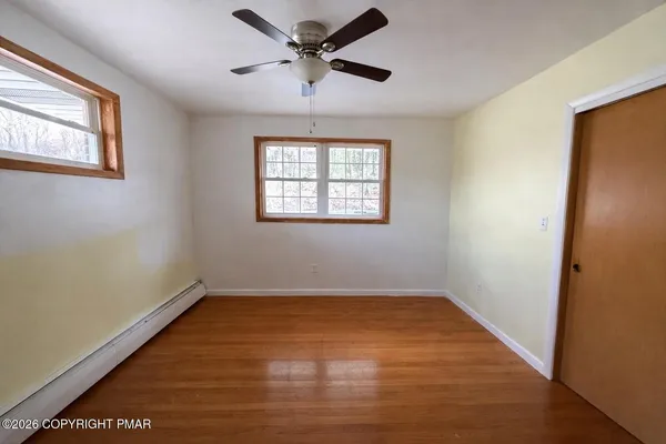 a view of empty room with wooden floor and fan