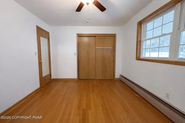 an empty room with ceiling fan and window