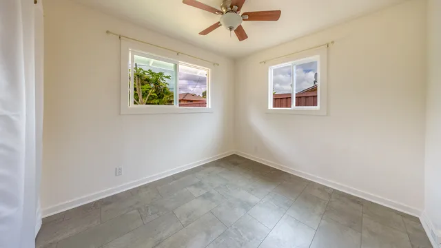an empty room with windows and ceiling fan