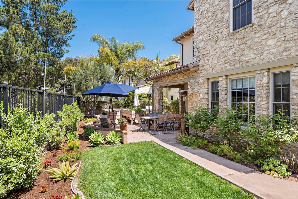 11 Pisano Street Ladera Ranch, CA 92694 - Photo 41 of 47 a view of a patio with table and chairs under an umbrella with potted plants