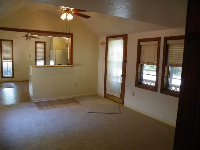 an empty room with chandelier fan and windows