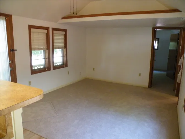 an empty room with a window and chandelier fan