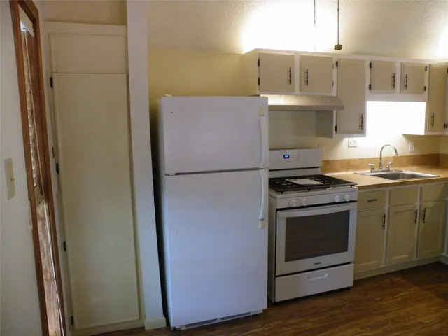 a kitchen with stainless steel appliances a refrigerator a sink a stove a dining table and chairs