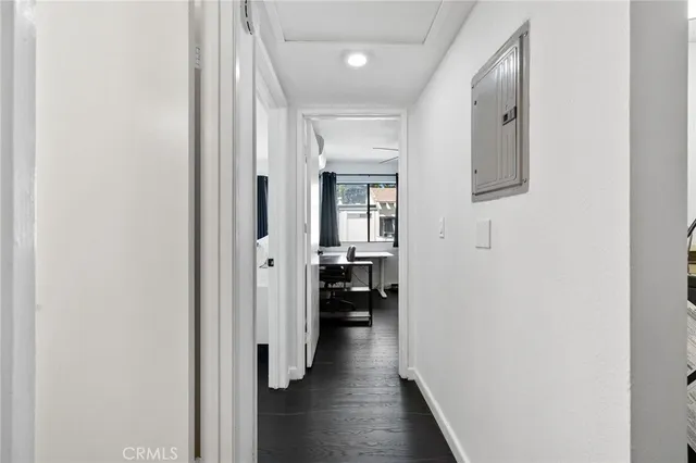 a view of a hallway with wooden floor and a bathroom