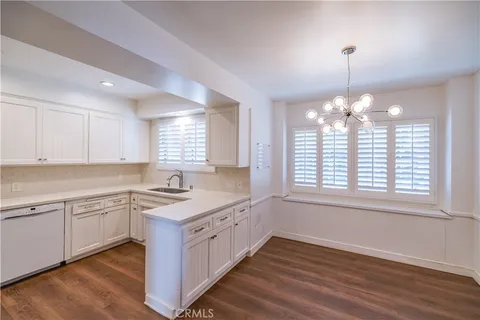 a kitchen with stainless steel appliances granite countertop a stove a sink and white cabinets with wooden floor
