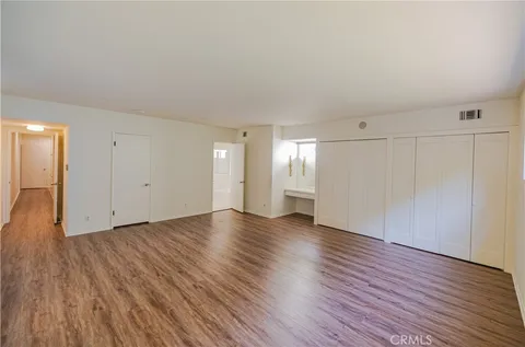 a view of an empty room with wooden floor and closet