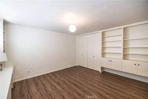 a view of a kitchen and an empty room with wooden floor and a window