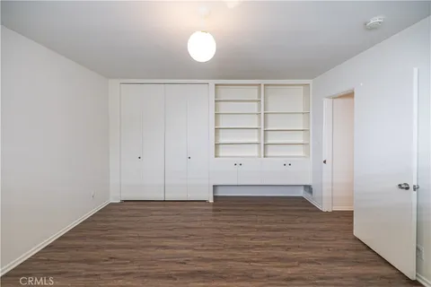 an empty room with wooden floor & closet and windows