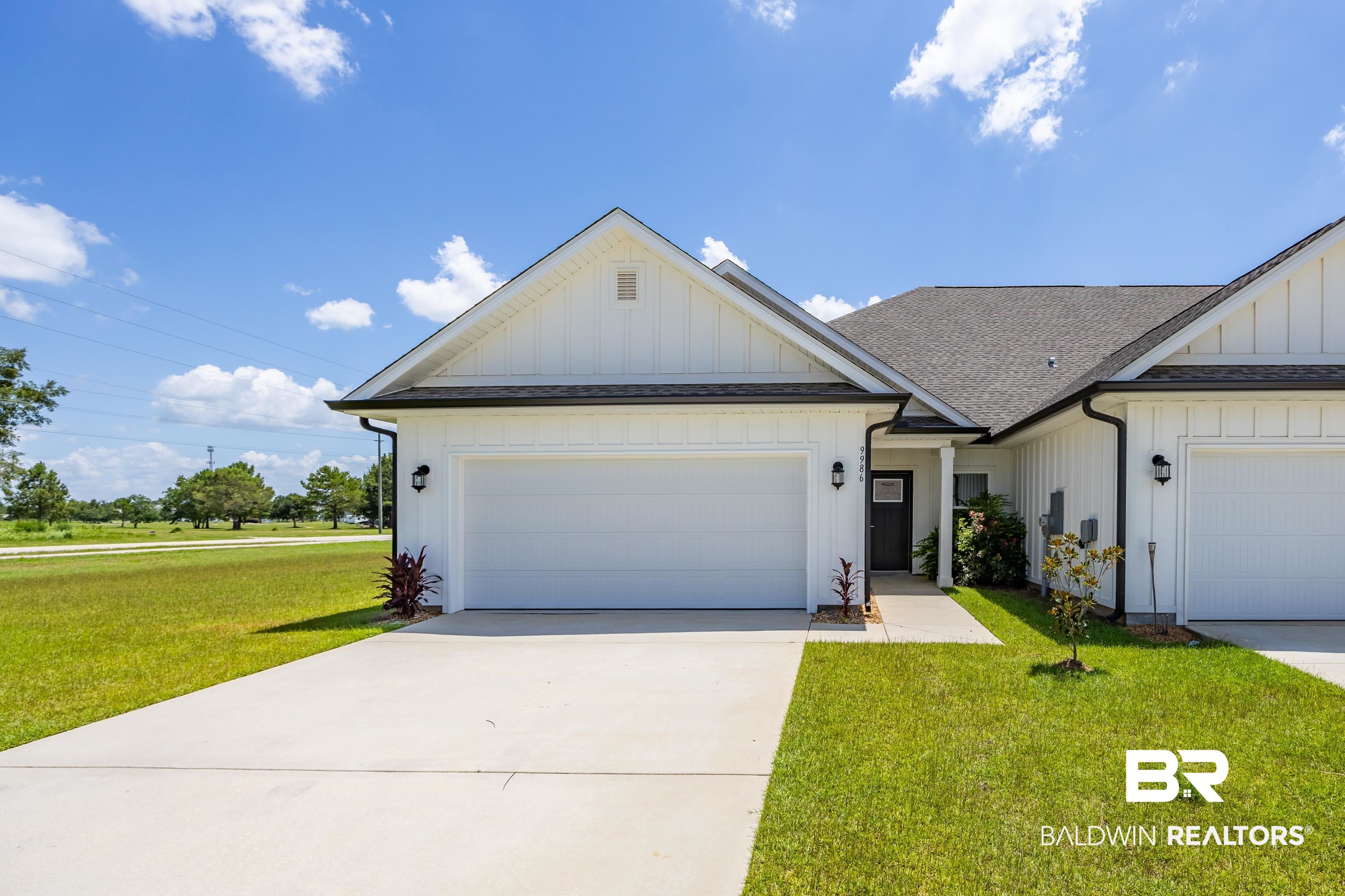 View of front of house with board and batten siding, roof with shingles, a front lawn, and a garage