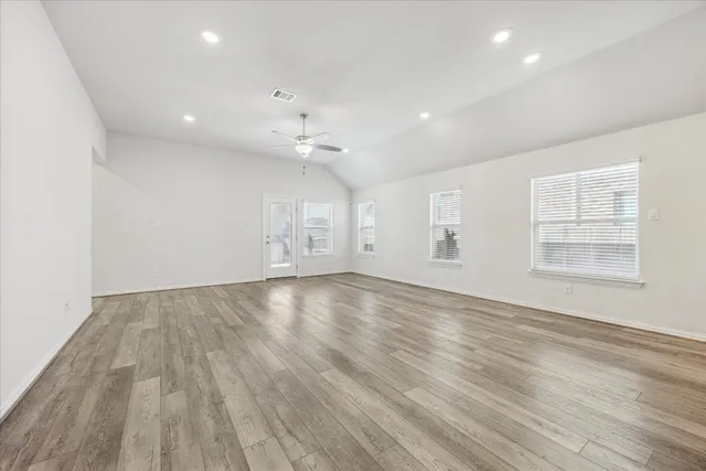 an empty room with wooden floor and windows