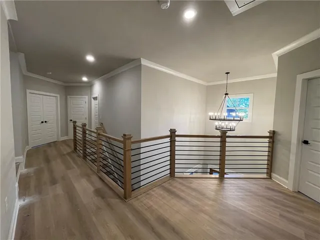a view of a hallway with stairs and wooden floor