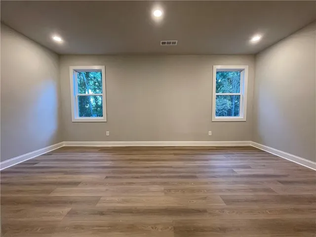 an empty room with wooden floor and windows