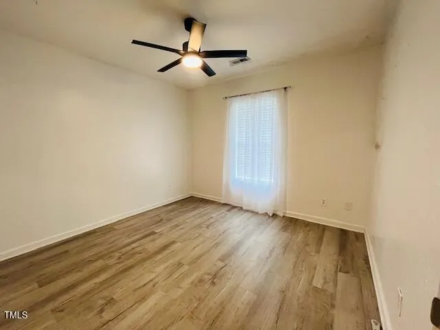 an empty room with wooden floor and a ceiling fan