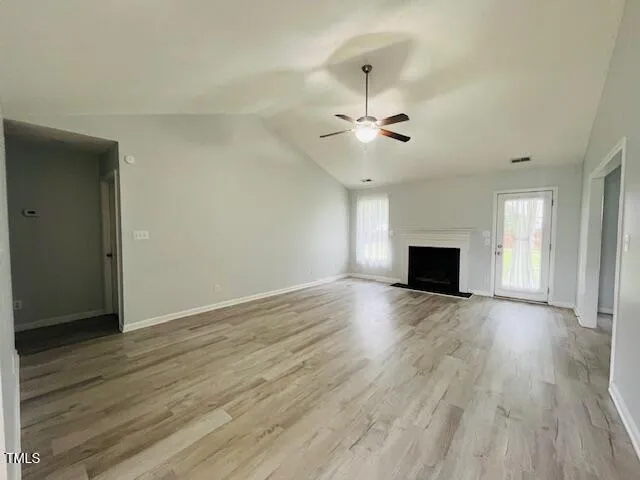 a view of empty room with wooden floor and fireplace