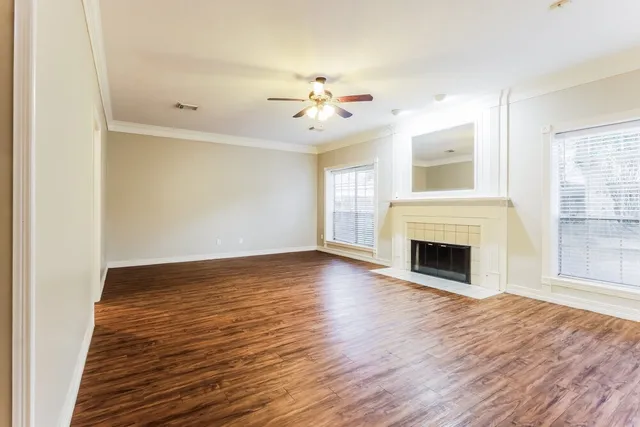 an empty room with wooden floor fireplace and windows