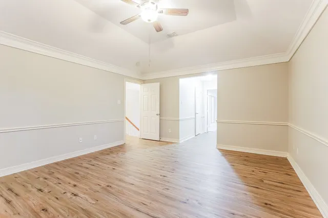a view of an empty room with wooden floor and a window