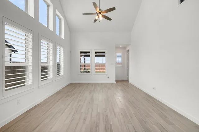 a view of an empty room with a window and wooden floor