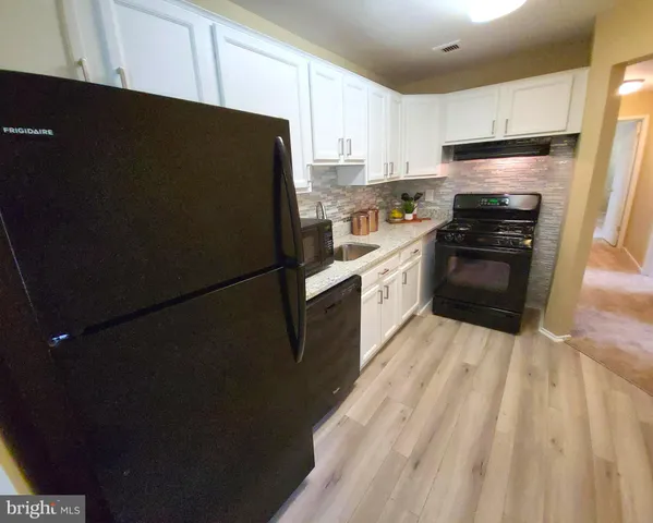a kitchen with granite countertop white cabinets and refrigerator