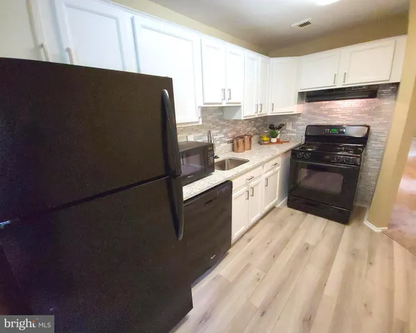 a kitchen with granite countertop white cabinets and white appliances