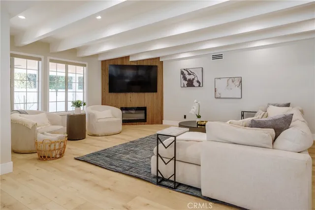 a living room with furniture a flat screen tv and floor to ceiling window