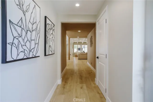 a view of a hallway with wooden floor and a bathroom