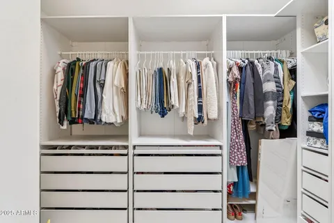 a view of walk in closet with clothes and shoes