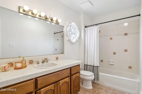 a bathroom with a granite countertop sink toilet a large mirror a shower and bathtub