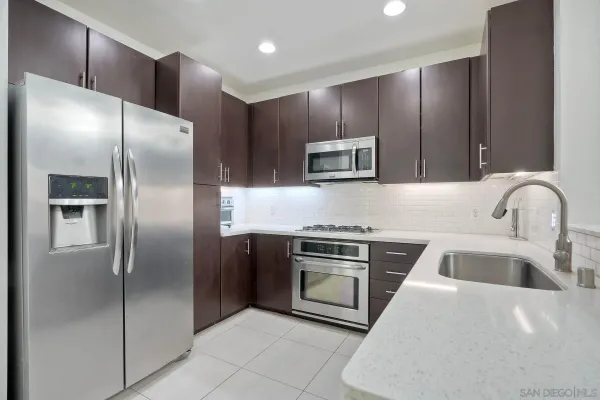 a kitchen with stainless steel appliances granite countertop a refrigerator a sink and a stove