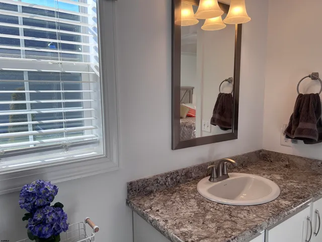 a bathroom with a granite countertop sink a large mirror and a window