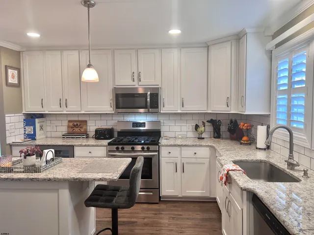 a kitchen with granite countertop a sink a counter top space appliances and cabinets