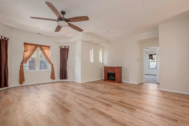 a view of empty room with wooden floor and fan