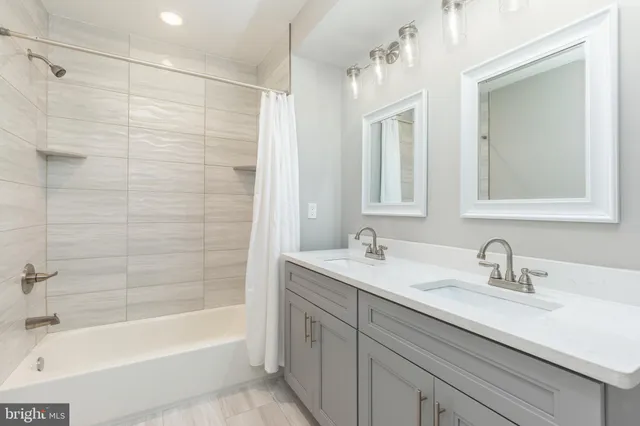 a bathroom with a sink double vanity granite tub shower and a mirror