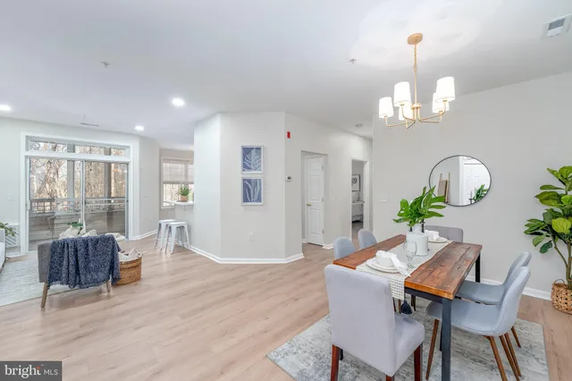 a dining room with wooden floor a chandelier a wooden table and chairs