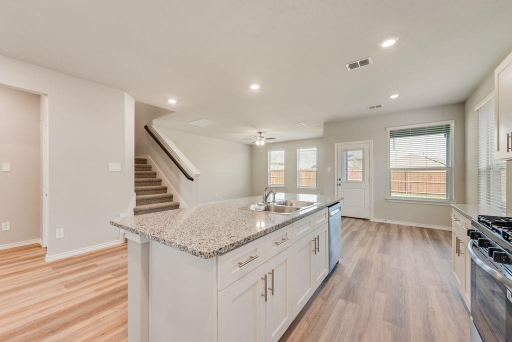 15944 Stableford Road Justin, TX 76247 - Photo 5 of 22 Chef's kitchen featuring white cabinetry, granite countertop island with seating, stainless steel gas range, recessed ceiling lighting, and wood-finish flooring