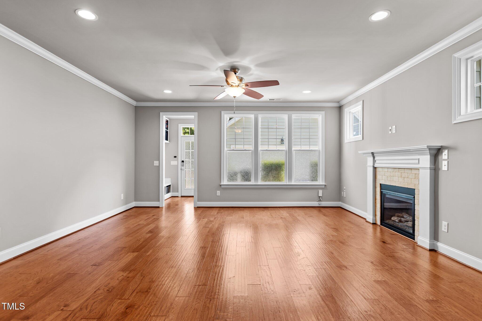 511 Mill Hopper Lane Apex, NC 27502 - Photo 14 of 53 an empty room with wooden floor fireplace and windows