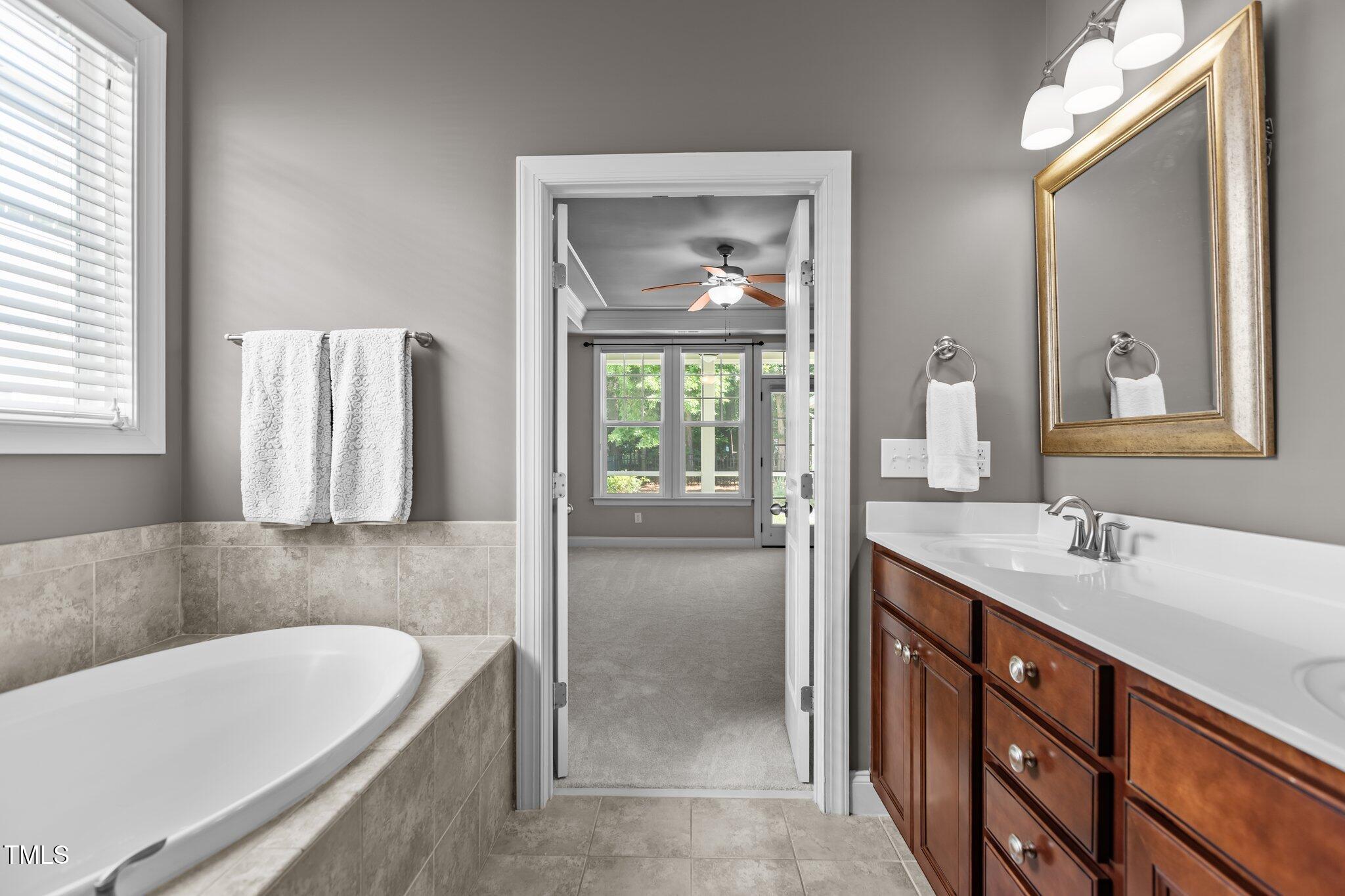 511 Mill Hopper Lane Apex, NC 27502 - Photo 24 of 53 a bathroom with a tub a double vanity sink and mirror
