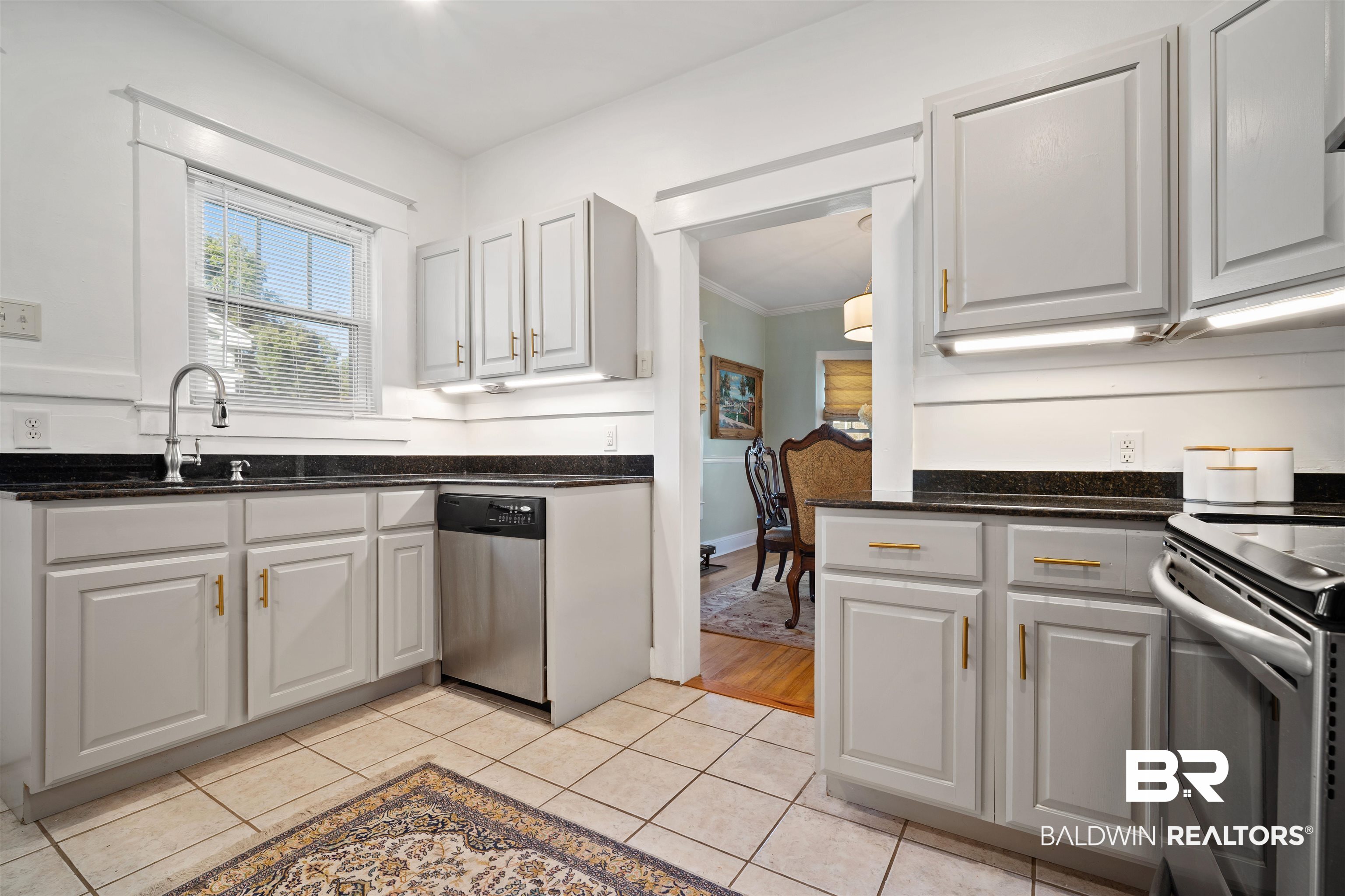 168 Mohawk Street Mobile, AL 36606 - Photo 10 of 31 Kitchen featuring dark stone countertops, stainless steel appliances, white cabinetry, light tile patterned floors, and crown molding