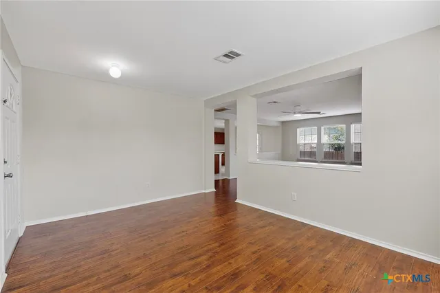 a view of a big room with wooden floor and windows