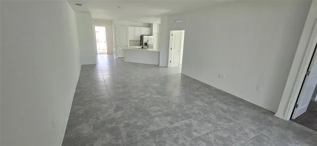 a view of kitchen and empty room with windows
