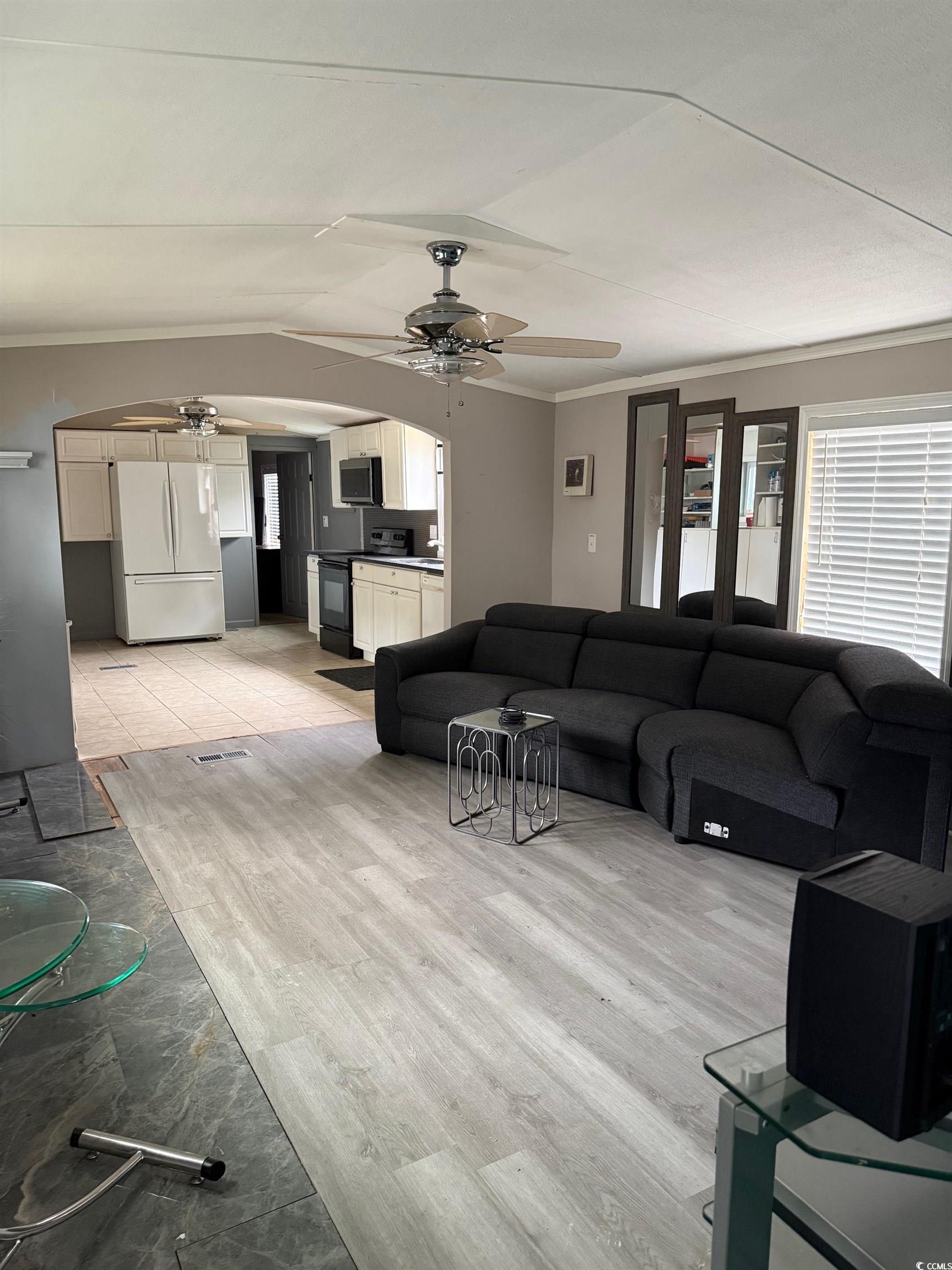 2709 Orion Drive Myrtle Beach, SC 29575 - Photo 11 of 27 Living area with crown molding, arched walkways, ceiling fan, vaulted ceiling, and light wood finished floors