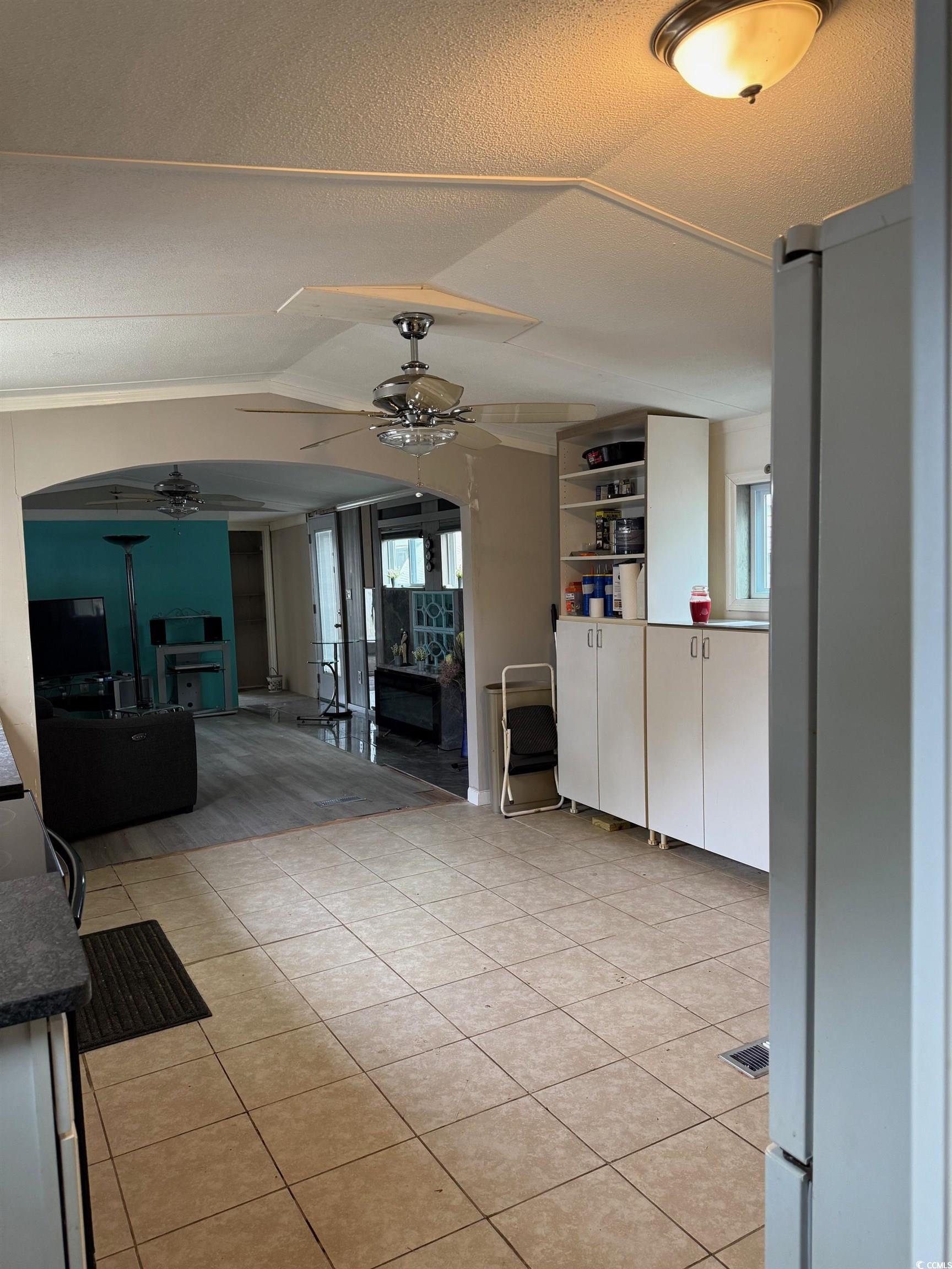 2709 Orion Drive Myrtle Beach, SC 29575 - Photo 14 of 27 Unfurnished living room featuring a ceiling fan, light tile patterned floors, vaulted ceiling, and a textured ceiling