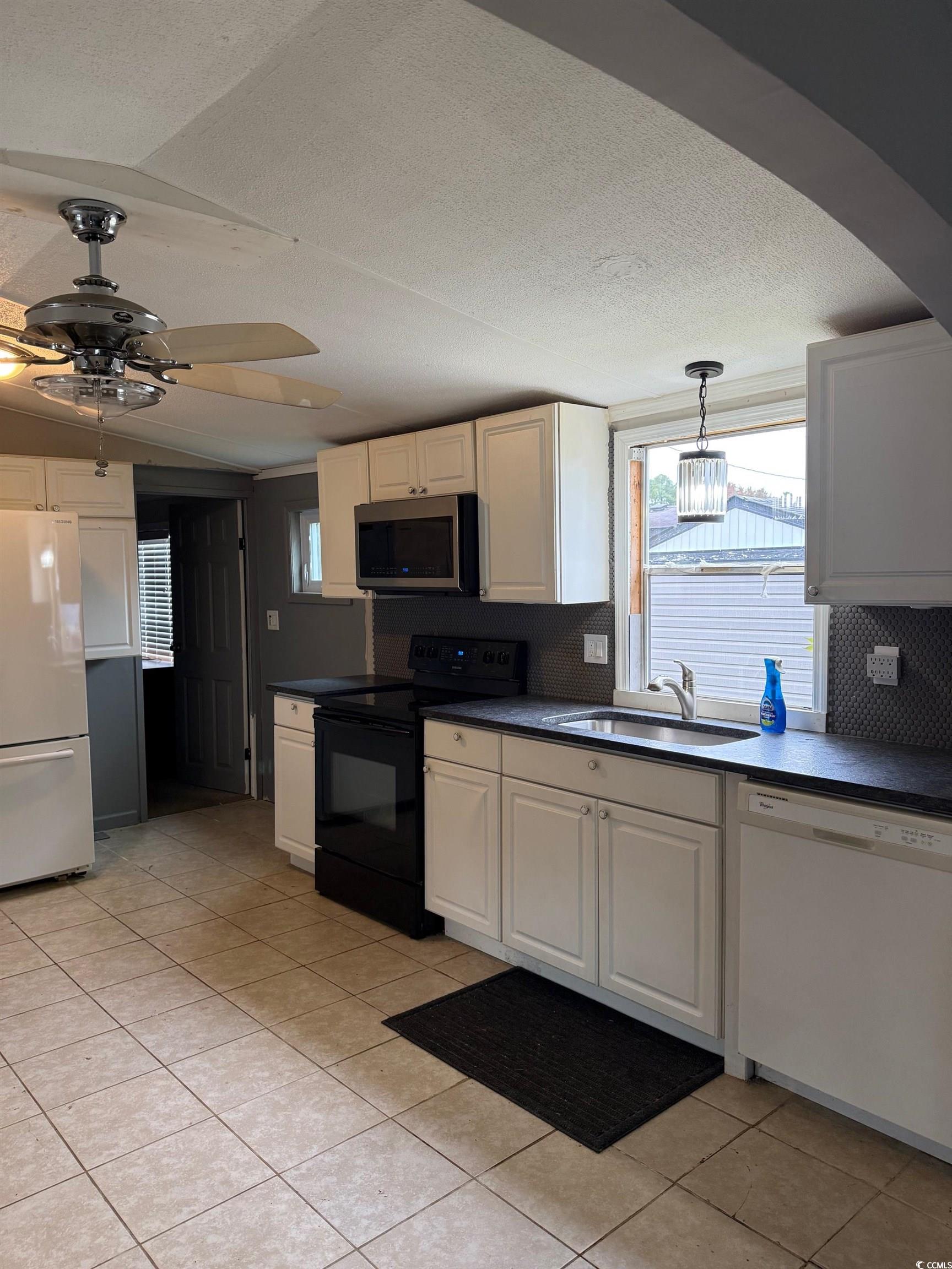 2709 Orion Drive Myrtle Beach, SC 29575 - Photo 15 of 27 Kitchen with white appliances, dark countertops, a textured ceiling, light tile patterned floors, and hanging light fixtures