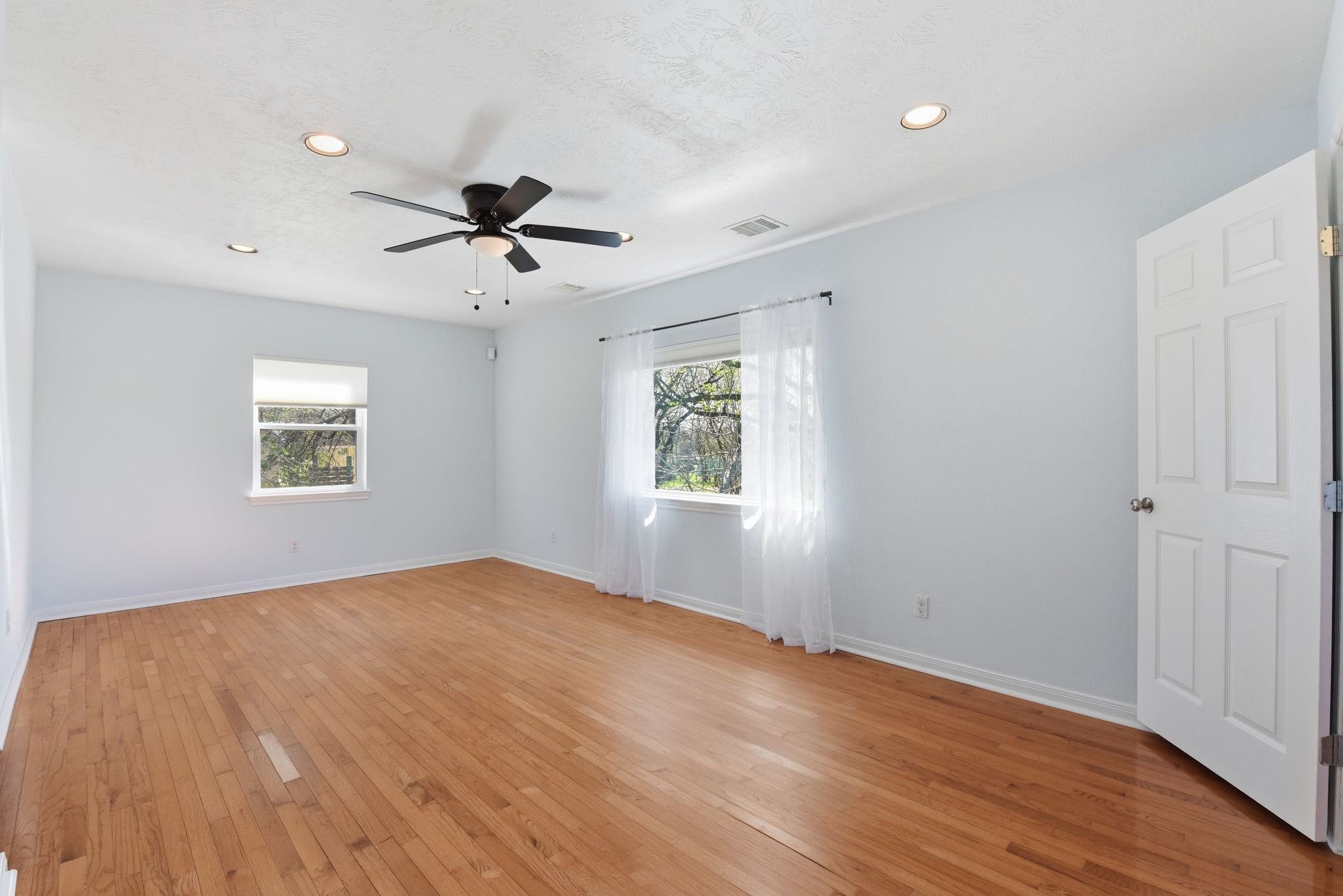 180 Grove Road Kemah, TX 77565 - Photo 16 of 30 This bright, unstaged primary bedroom offers a spacious canvas with gleaming hardwood floors, a sleek ceiling fan, and abundant natural light, ready for your personal touch.